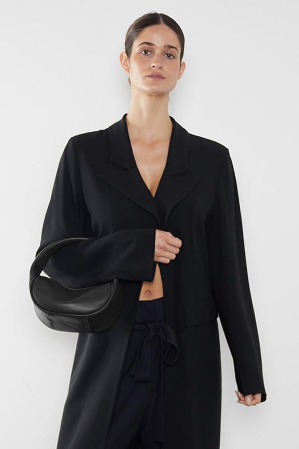 A woman carrying the Mini Halo bag in the crook of her arm. It shows the front angle of the handbag with its petite structured body.