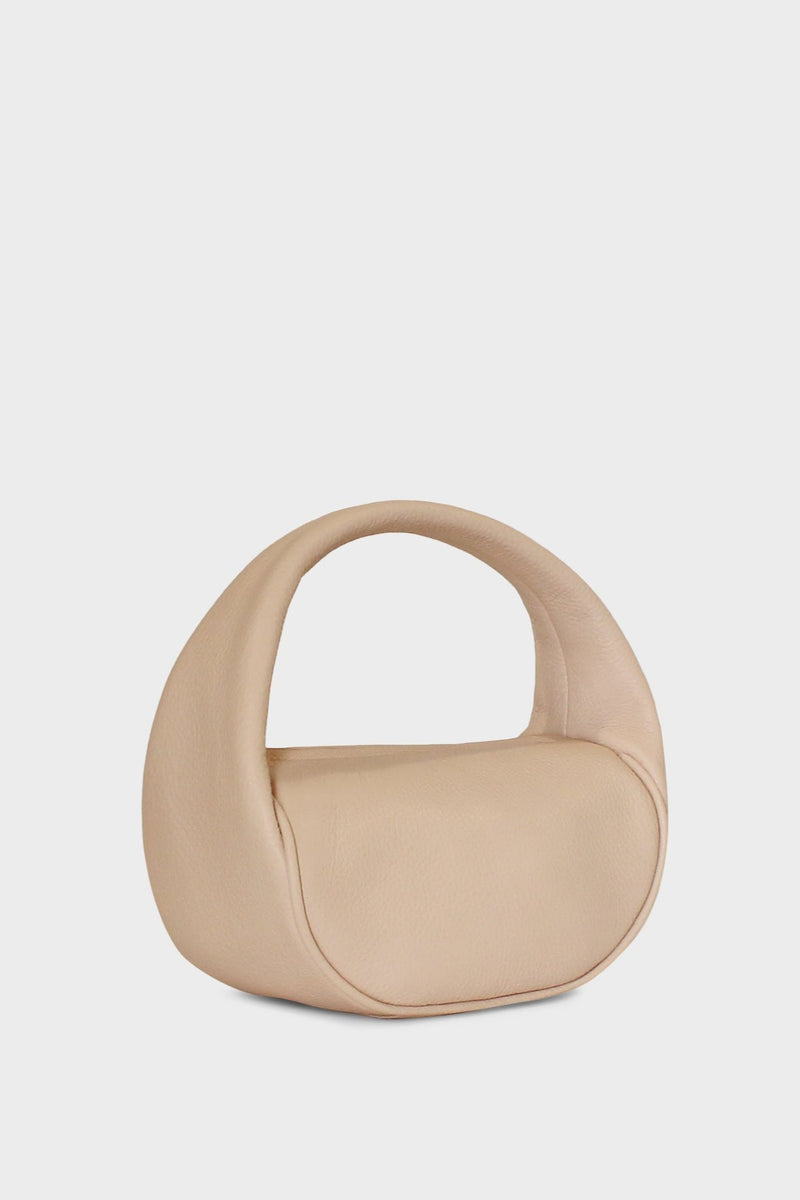 A side image of the mini halo bag in pastel pink.  This handbag has a clutch like design and can be worn handheld or on the crook of the arm suited as a party or evening purse.