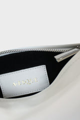 The mini halo bag has a black suede interior lining with an A-esque tag sewn inside. The shoulder bag features a silver hardware zipper. This small clutch purse is called Mini Halo Bag in Smooth Off White.