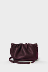 A burgundy mini clutch bag made of smooth Italian leather.with a long removable and adjustable strap for crossbody wearing.