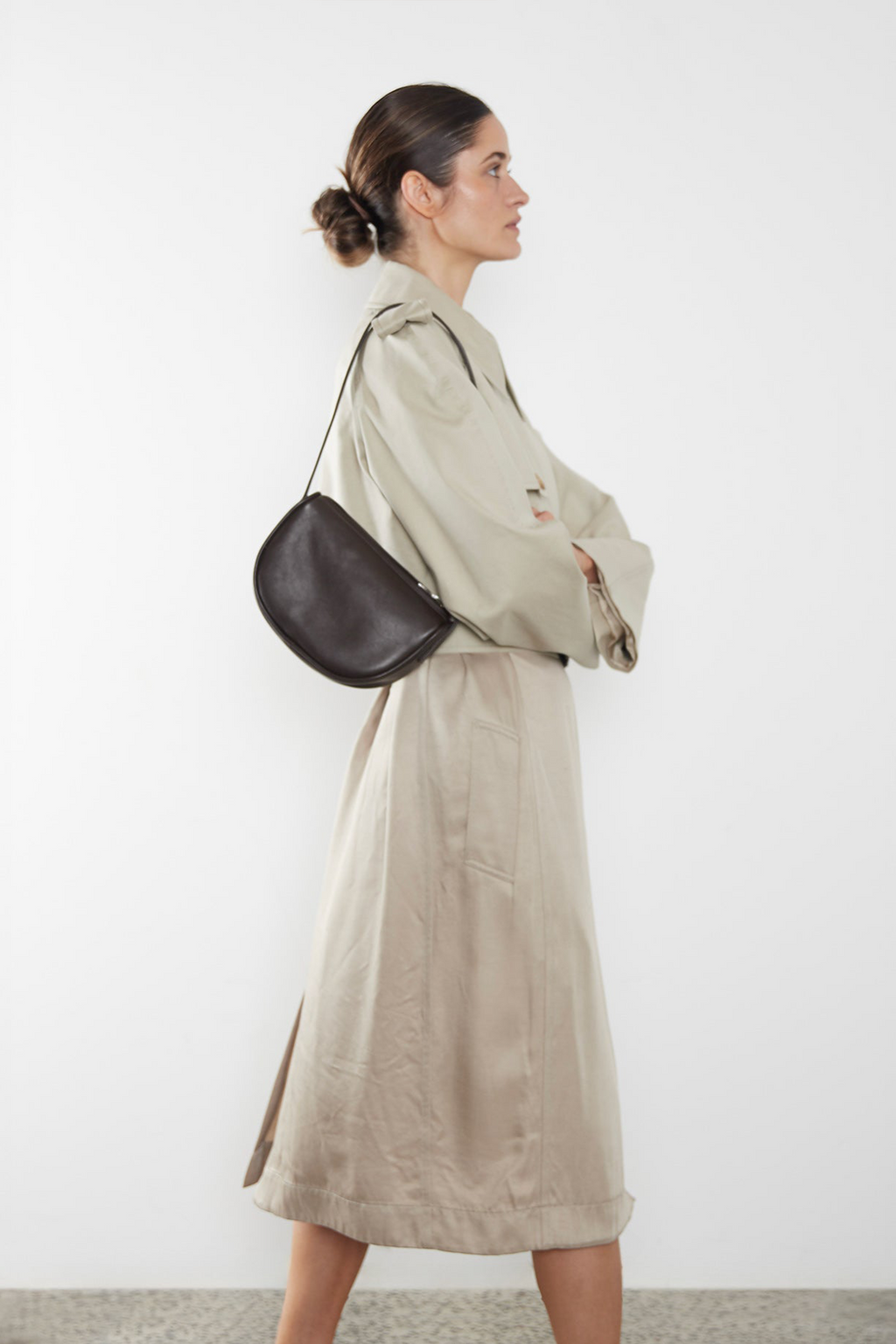 A woman wearing a small shoulder bag. It shows the front angle of the bag and its small compact body.