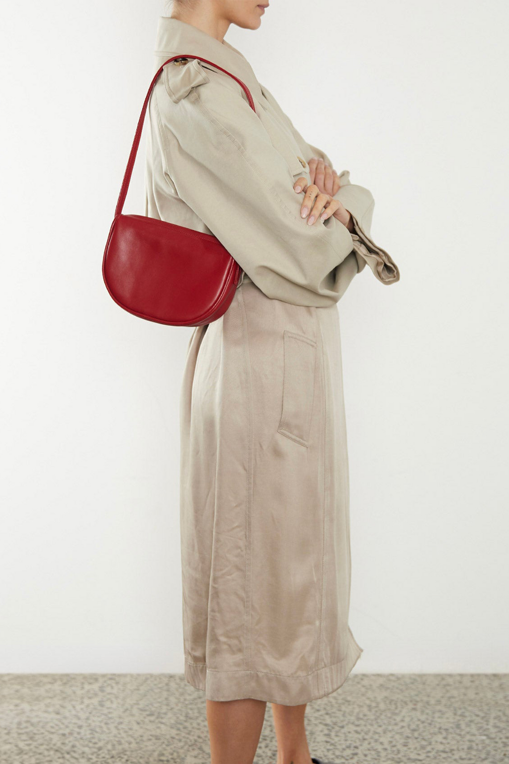 A woman wearing a small shoulder bag. It shows the front angle of the bag and its small compact body.