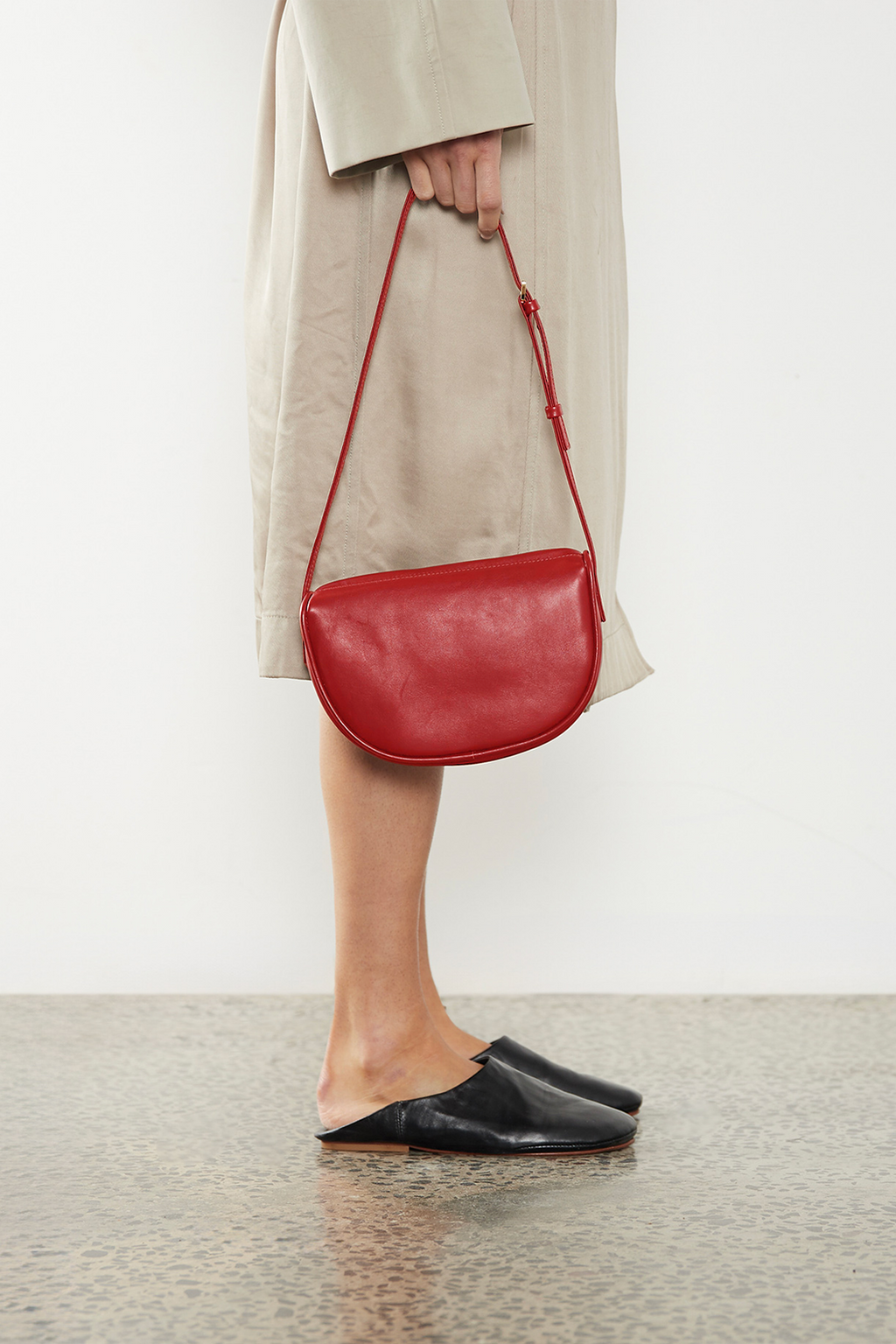 A woman carrying the mini saddle shoulder bag through its handle. It highlights a fusion of hobo and saddle bag design inspiration. 