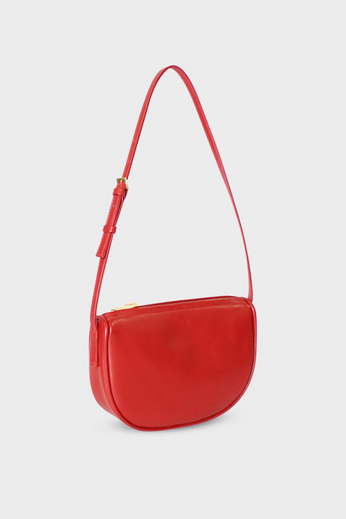 A side angle of the red mini saddle shoulder bag. It features a sturdy gusset with an adjustable handle strap and gold hardware.