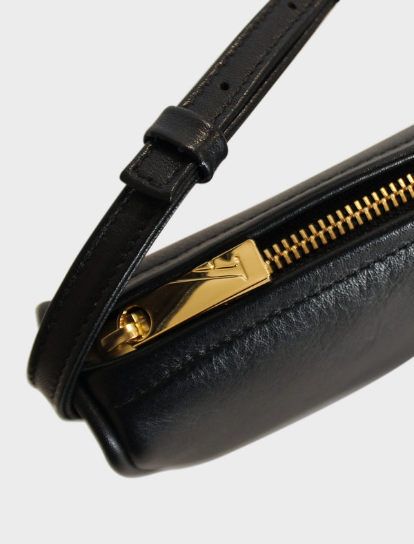 The mini saddle shoulder bag features a gold hardware and zippers. This image features the mini bag's zipper with the initial A which stands for A-esque, the brand's name.