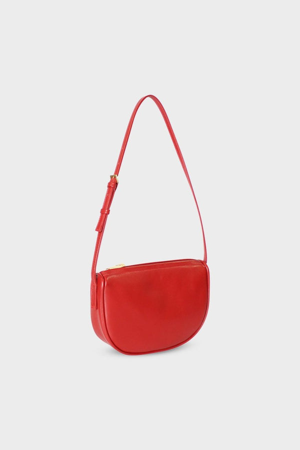 A side image of a shoulder bag in the color red. The mini bag  follows a saddle like design with a slim body. The bag is called Mini Saddle Shoulder Bag in Smooth Red.