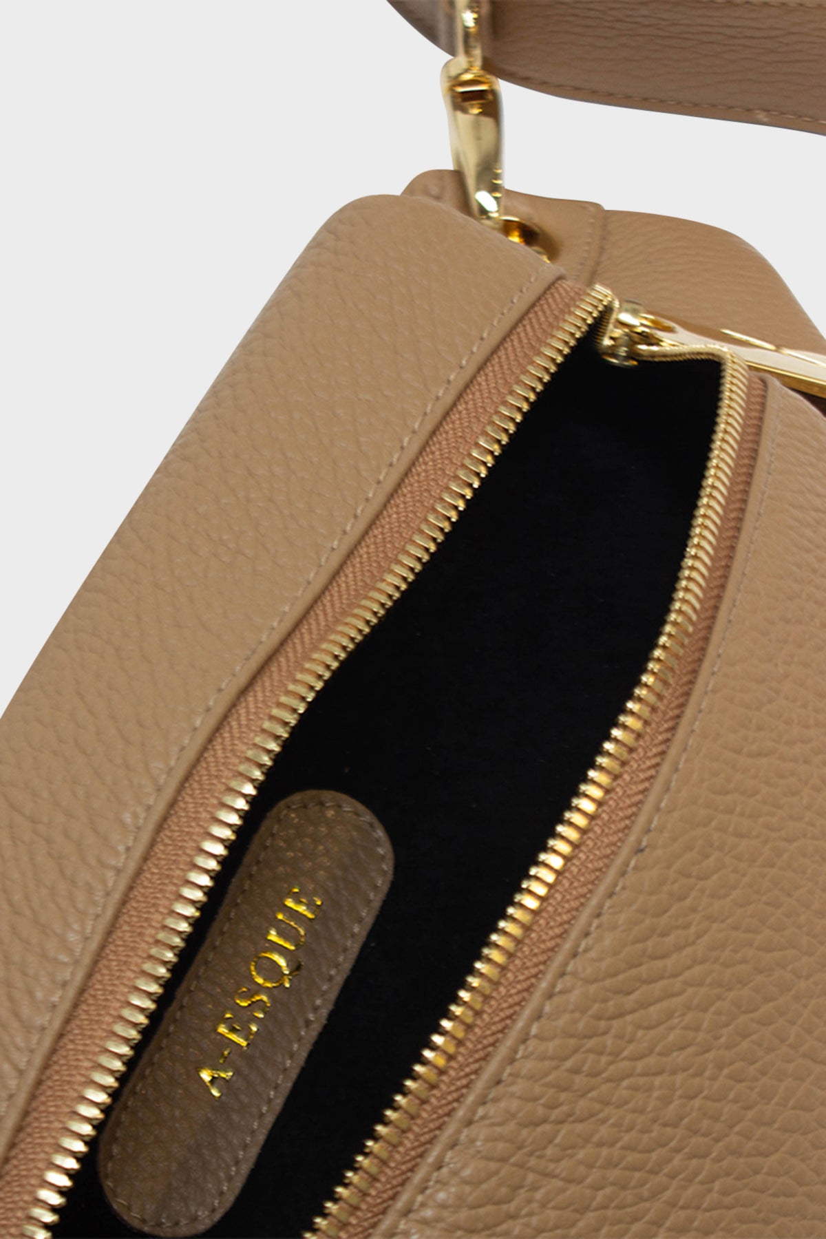 The oblong crossbody bag's interior is lined in suede with an embossed A-esque logo in the middle.