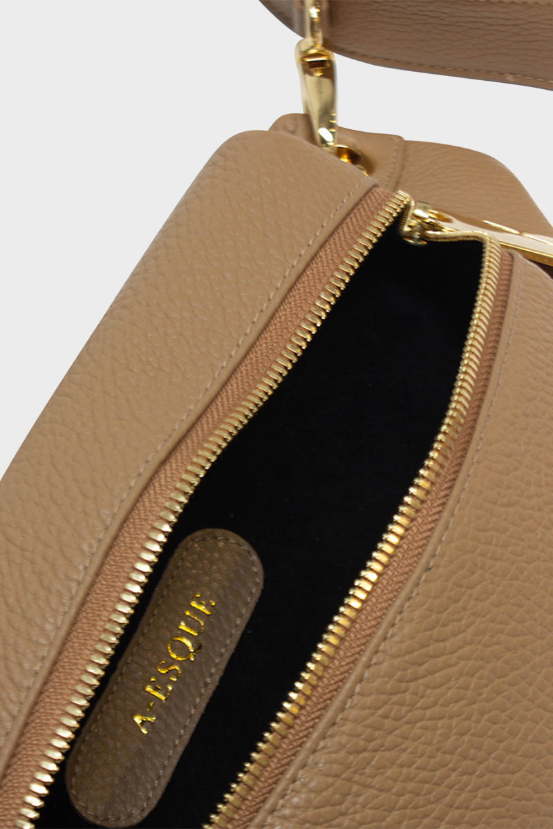 The oblong crossbody bag's interior is lined in suede with an embossed A-esque logo in the middle.