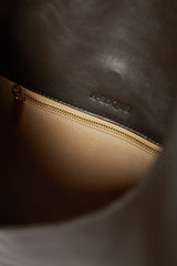 The photo shows the interior of the hoboshoulder bag. It has a zipped pocket with gold hardware. The interior is lined with a tan suede leather. 