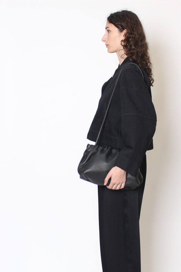 A woman carrying the Puffa clutch with its strap slung in the shoulder. The bag can be both handheld or worn as a crossbody bag.