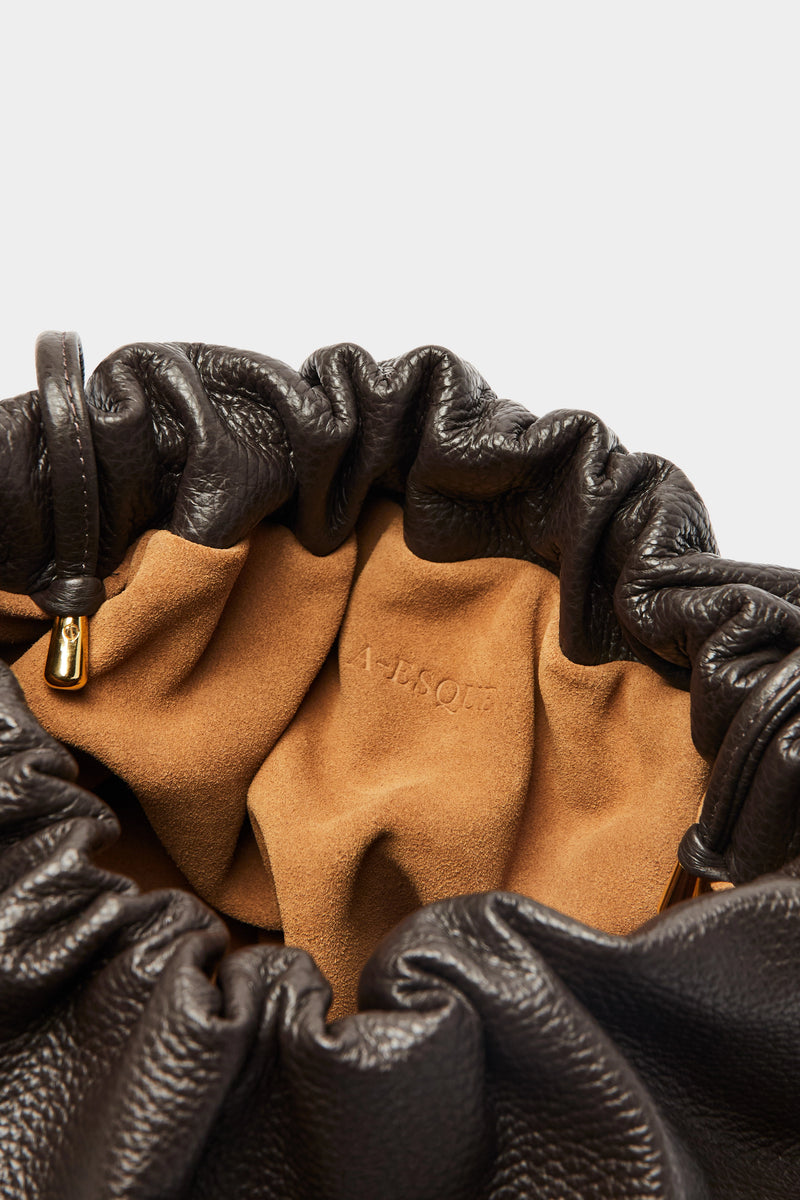 Puffa clutch crossbody bag has a suede interior lining with an A-esque logo stamped in the middle. 