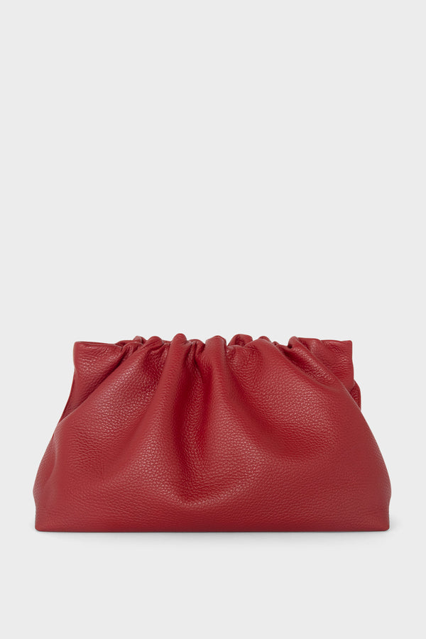 A red clutch bag made of grain Italian leather. The handbag has a removable strap and can also be worn as a crossbody bag.