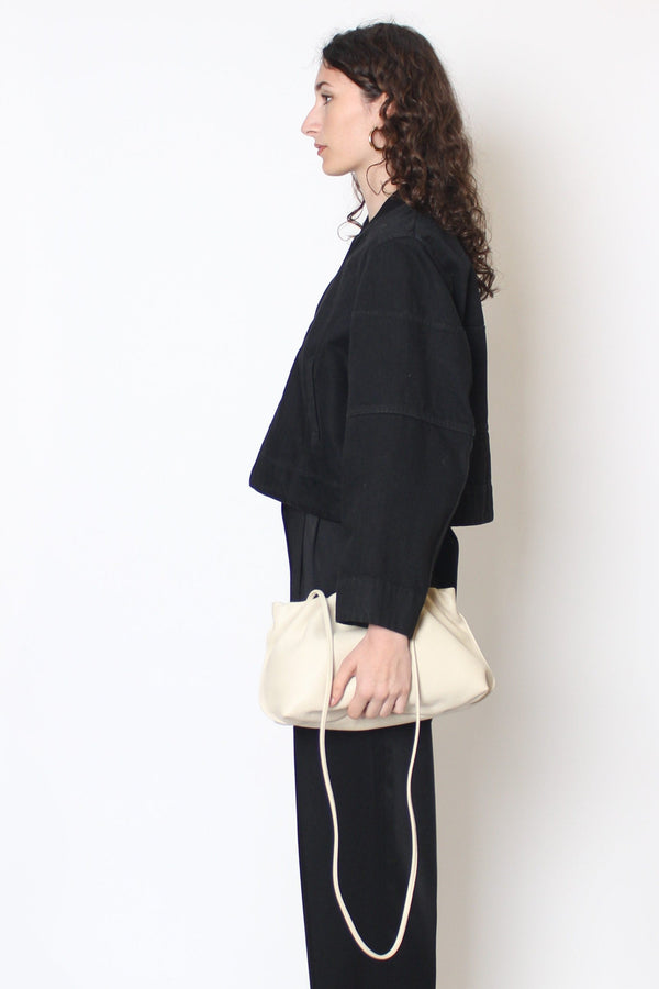 A woman carrying the Puffa clutch handheld with its long removable strap hanging. 