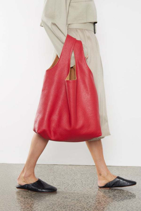 A woman carrying the tote bag in the crook of her arm. The bag can be carried handheld and is also suited as a travel bag.