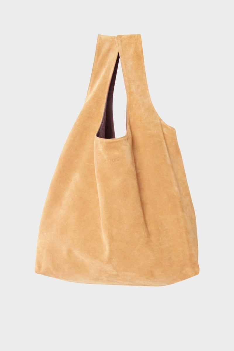 The reversible tote bag in its tan suede side. The bag is convertible into 2 colors with One side in burgundy smooth leather and the other side in tan suede leather. Worn as a large shoulder bag, it can carry everyday essentials and can be used as a beach bag or travel bag.