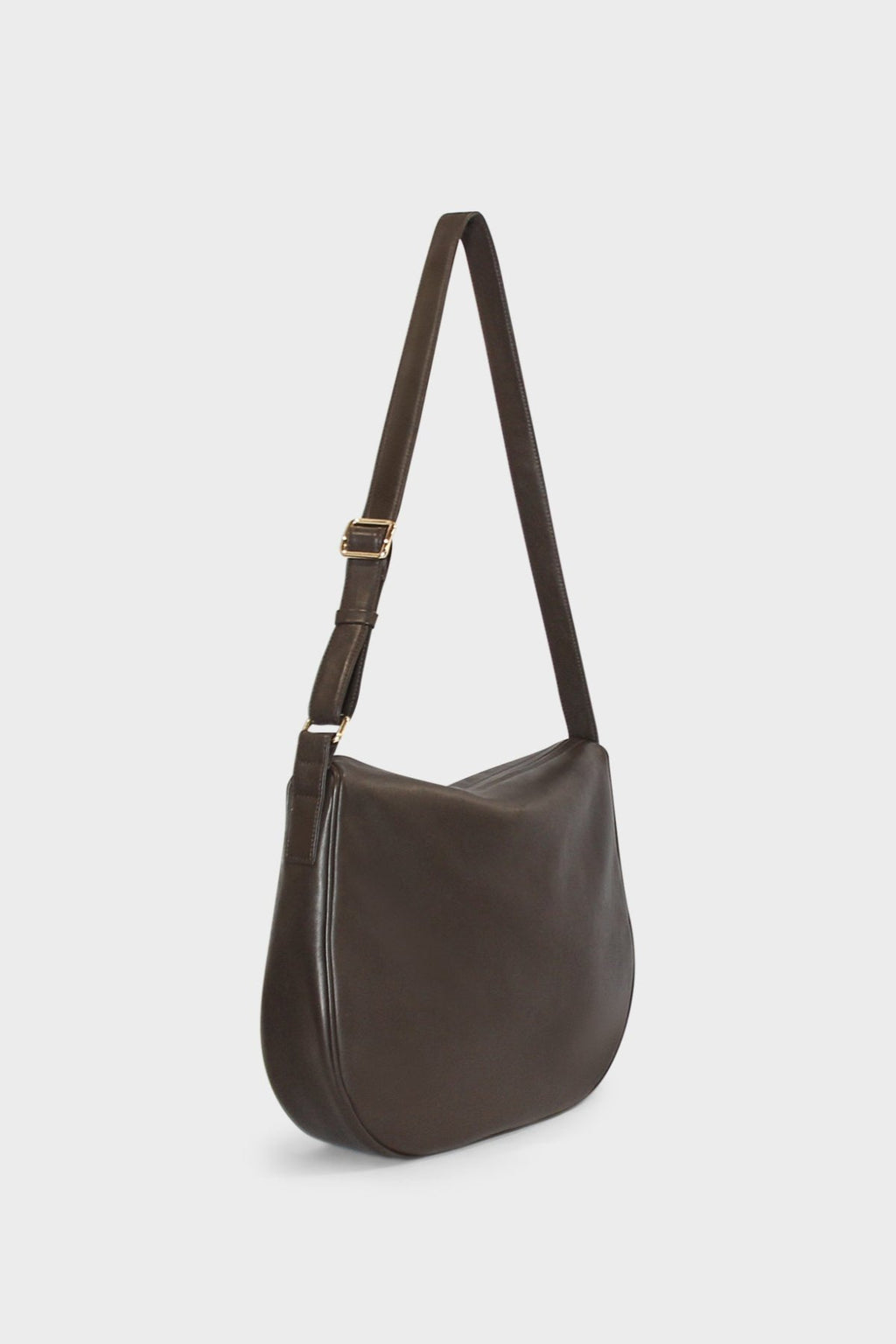 A side image of a crossbody bag that follows a satchel like design. The bag is large but has a slim body.The bag is called Saddle Large Crossbody Bag in Smooth Dark Brown.