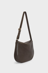 A side image of a crossbody bag with a hobo satchel design. The bag is large with a slim body and adjustable strap.