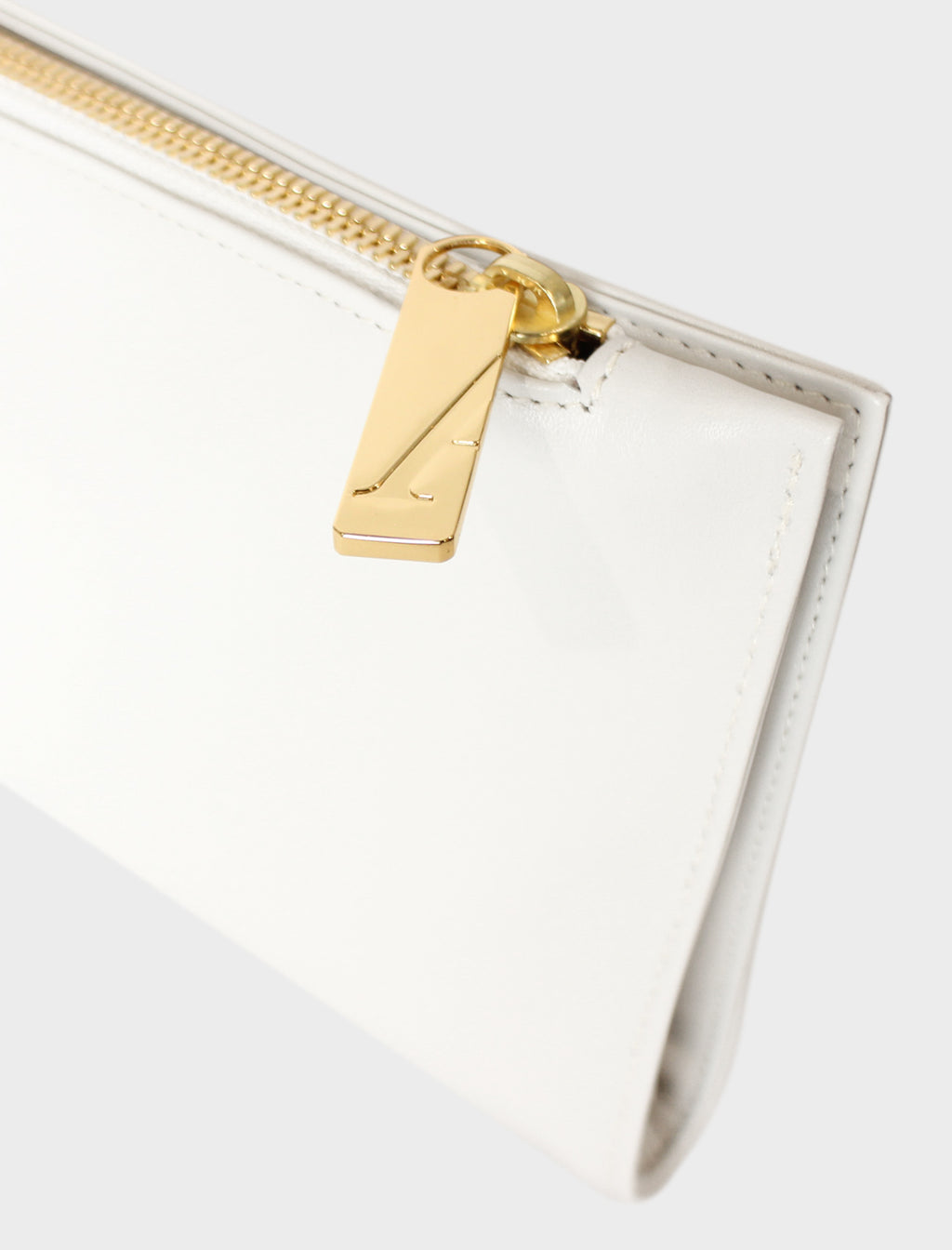 The slimline clutch pouch features a gold hardware and durable zipper and magnetic closures. This image features the clutch zipper with the initial A which stands for A-esque, the brand's name.