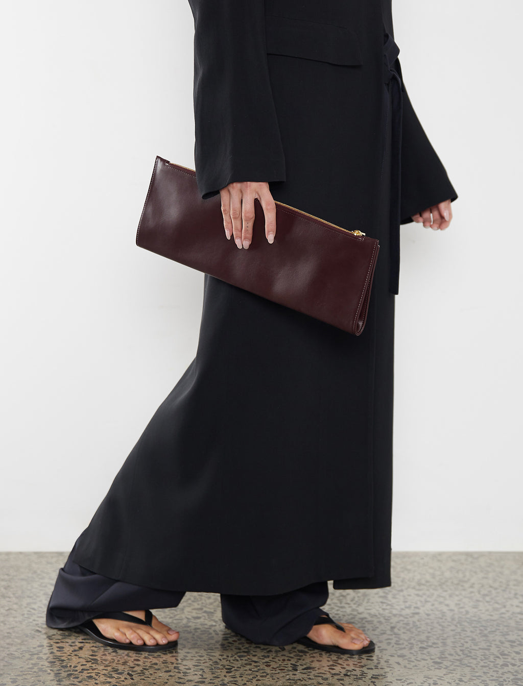 A woman carrying the red slimline clutch pouch. The clutch is folded and looks like a long wallet. It's suited as a party clutch or a casual pouch or purse.