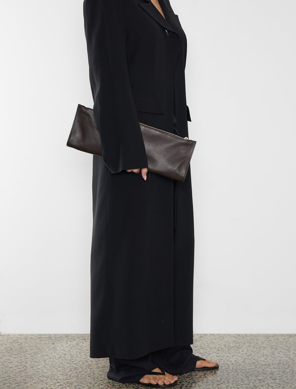 A woman carrying the red slimline clutch pouch. The clutch is folded and looks like a long wallet. It's suited as a party clutch or a casual pouch or purse.