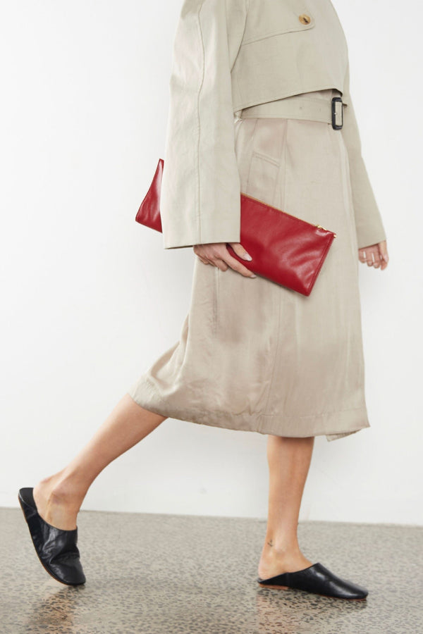 A woman carrying the red slimline clutch pouch. The clutch is folded and looks like a long wallet. It's suited as a party clutch or a casual pouch or purse.