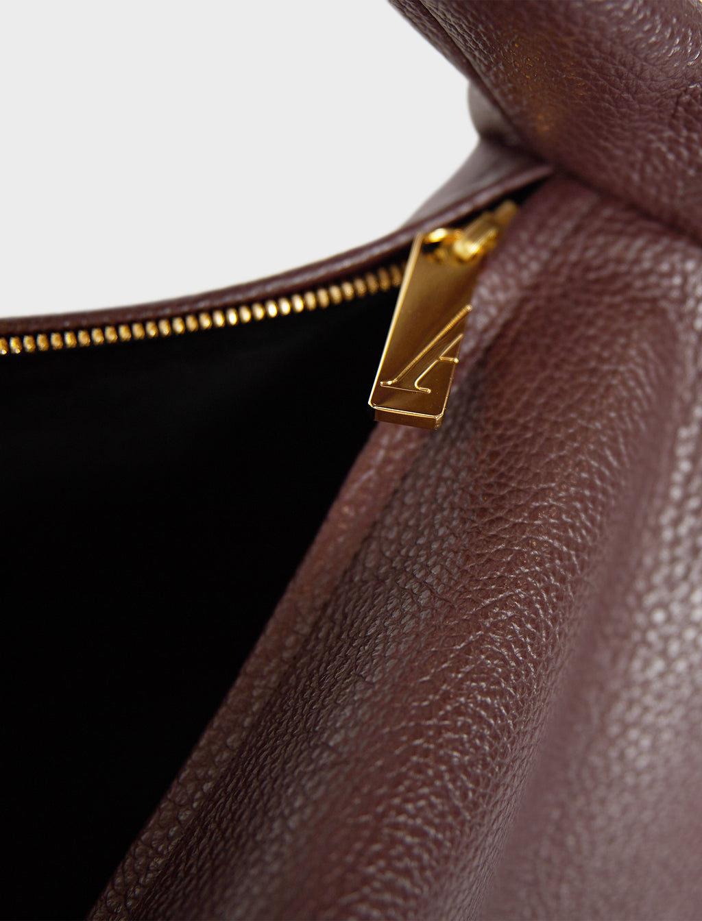 The large saddle shoulder bag features a gold hardware and durable zippers. This image features the satchel's zipper with the initial A which stands for A-esque, the brand's name.