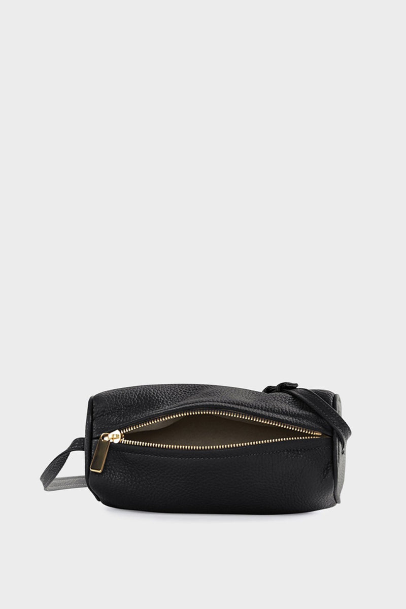 The small black barrel shoulder bag uses gold hardware and zipper with a white suede lining inside.