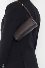 A woman carrying the small barrel shoulder bag. It highlights the elongated yet slim and compact design of the handbag.