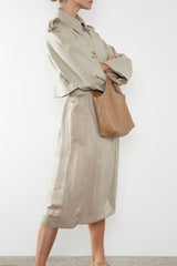 A woman carrying the small reversible beige handbag slung in the crook of the arm. This mini bag suits as a casual everyday purse bag.