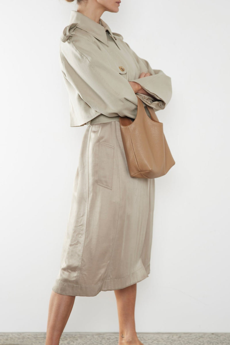 A woman carrying the small reversible beige handbag slung in the crook of the arm. This mini bag suits as a casual everyday purse bag.