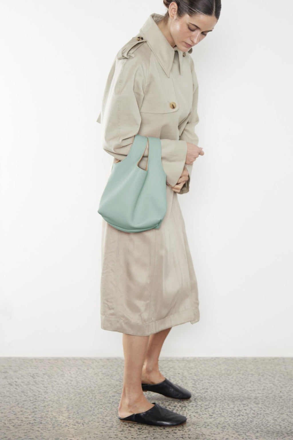 A woman carrying the small reversible handbag slung in the crook of the arm. This pastel green mini bag suits as a casual everyday purse bag.