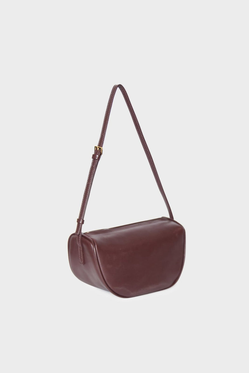 The side angle of the small saddle shoulder bag features a structured and slightly wide body.