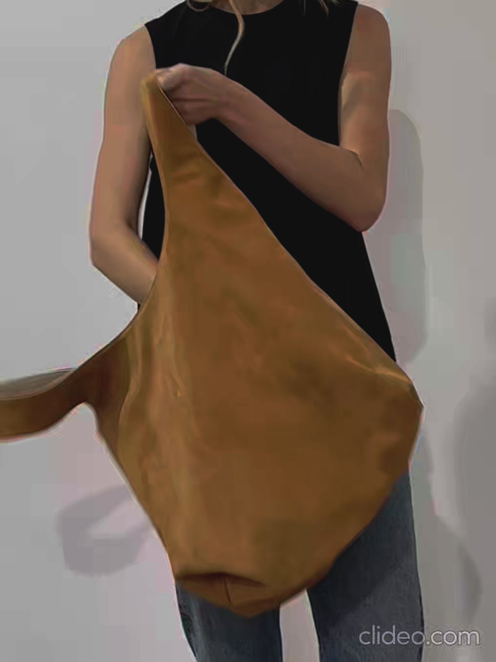 A video of a woman showing the reversible feature of the tote bag in its white grain leather and brown suede side. 