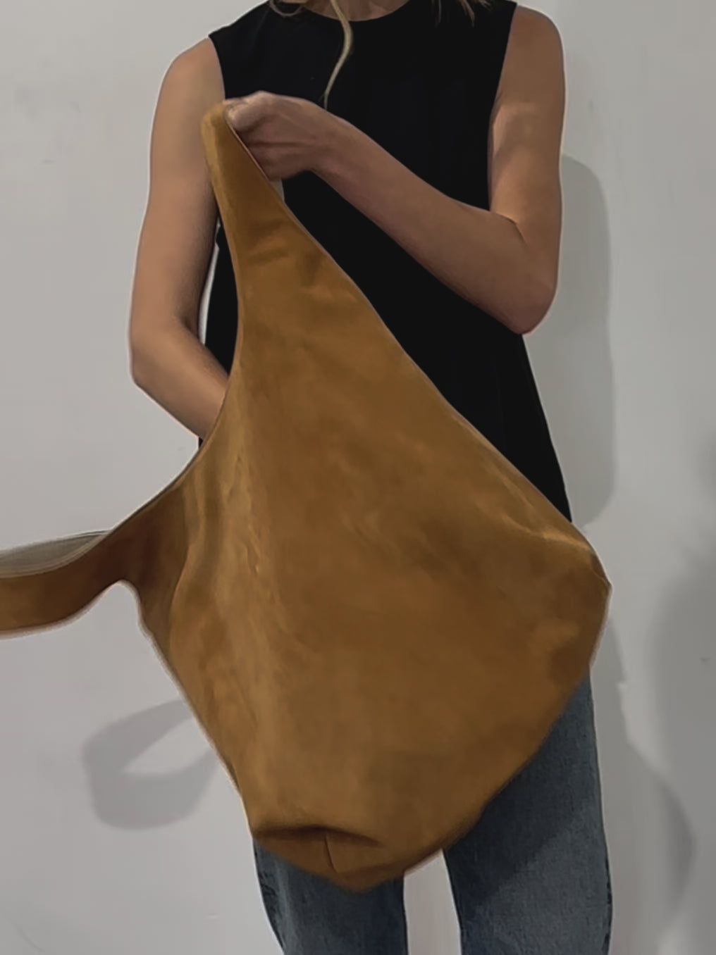 A video of a woman showing the reversible feature of the tote bag in its white grain leather and brown suede side.