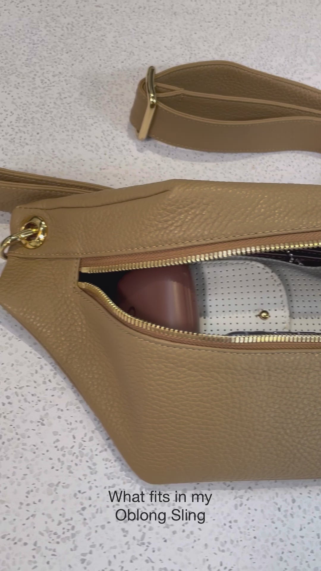 A video of what fits inside the Oblong Crossbody bag. It can easily fit a cardholder, sun glasses, aipods, lipstick, keys, and an iphone.